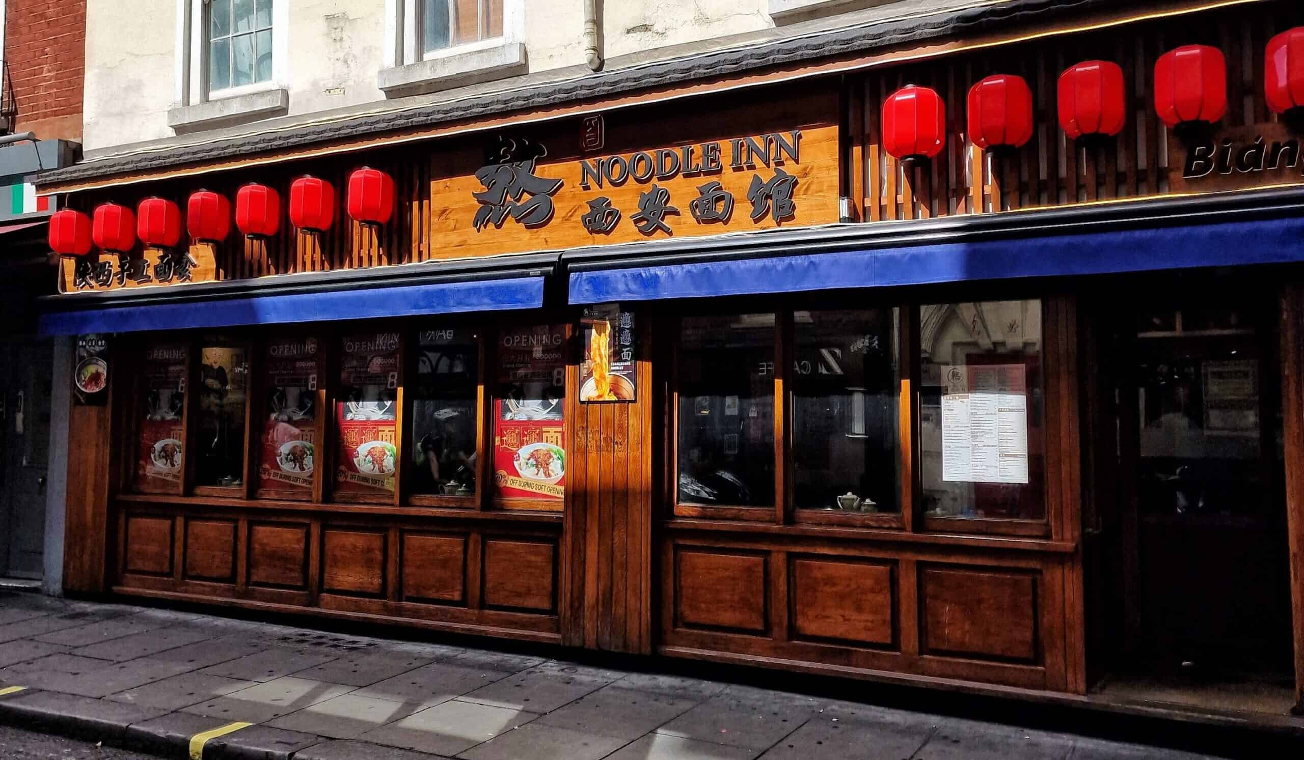 Noodle Inn restaurant exterior with red lanterns and wooden facade in Chinatown.
