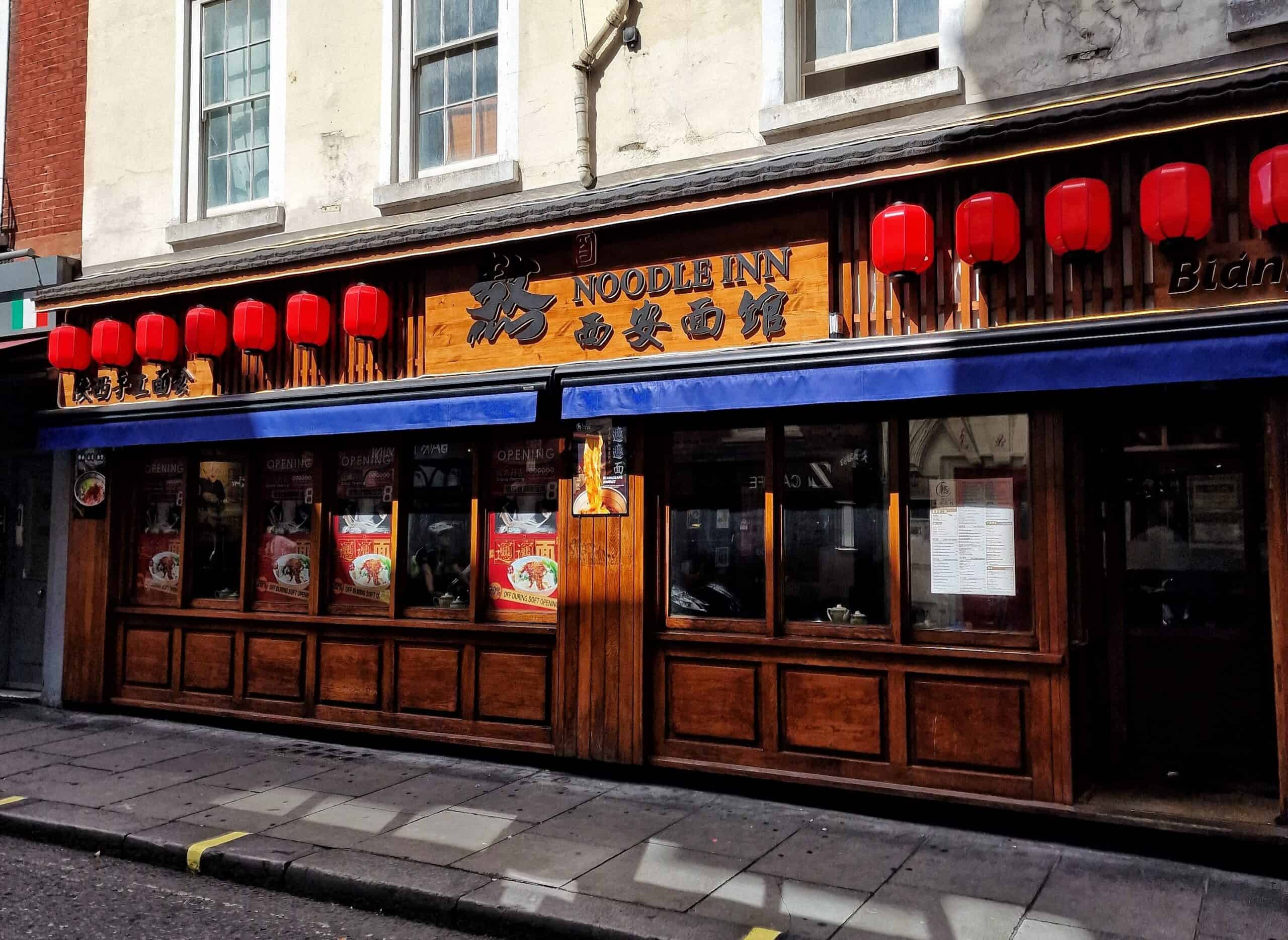 Noodle Inn restaurant exterior with red lanterns and wooden facade in Chinatown.